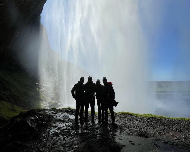 A silhouette of 4 friends standing behind a waterfall in Iceland