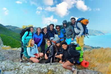 a group of students pose for a photo while on a hike through New Zealand's coast