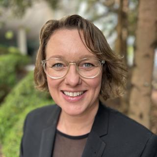 Woman with short brown hair with glasses outside