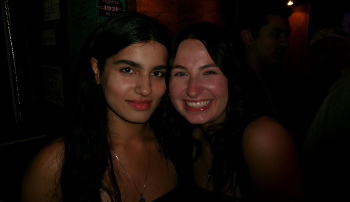 A close-up of two friends, indoors, dim lighting 