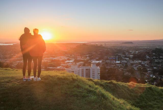 two students watch the sunset atop Mount Eden in Auckland