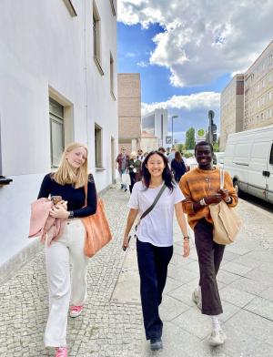 Three students walk on the sidewalk in Berlin, Germany.