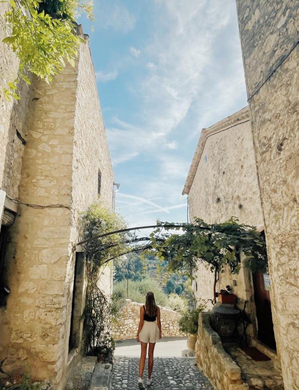 female standing on cobblestones in between stone buildings
