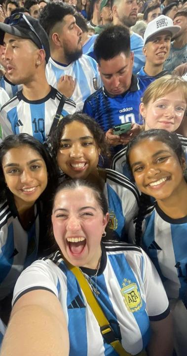 a group of students in Argentina futbol jersey's in a crowd