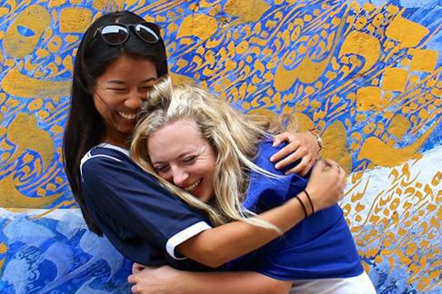 two students laughing while hugging